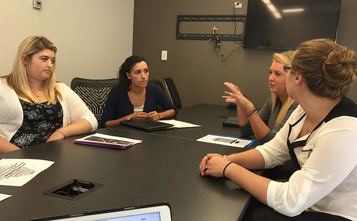 Photo of BW students sitting at a conference table discussing marketing plans